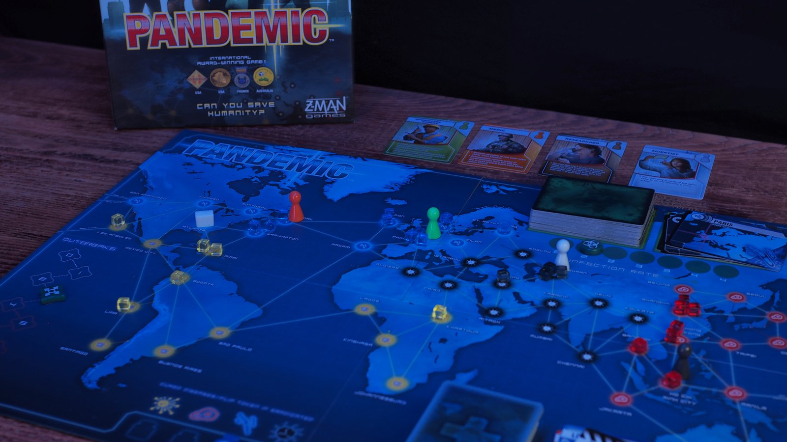 The Pandemic board with tokens, cards, and box arrayed on a wooden table