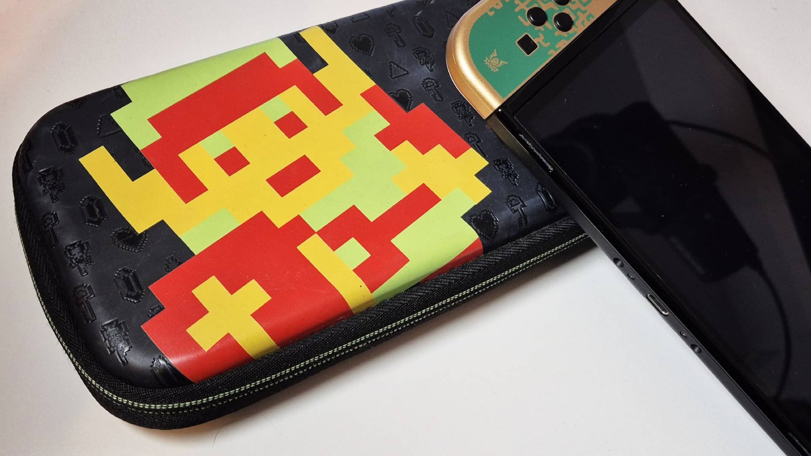 Image of the official PDP 'Retro Link' original Switch case, with the Tears of the Kingdom OLED Switch sitting on top of it.