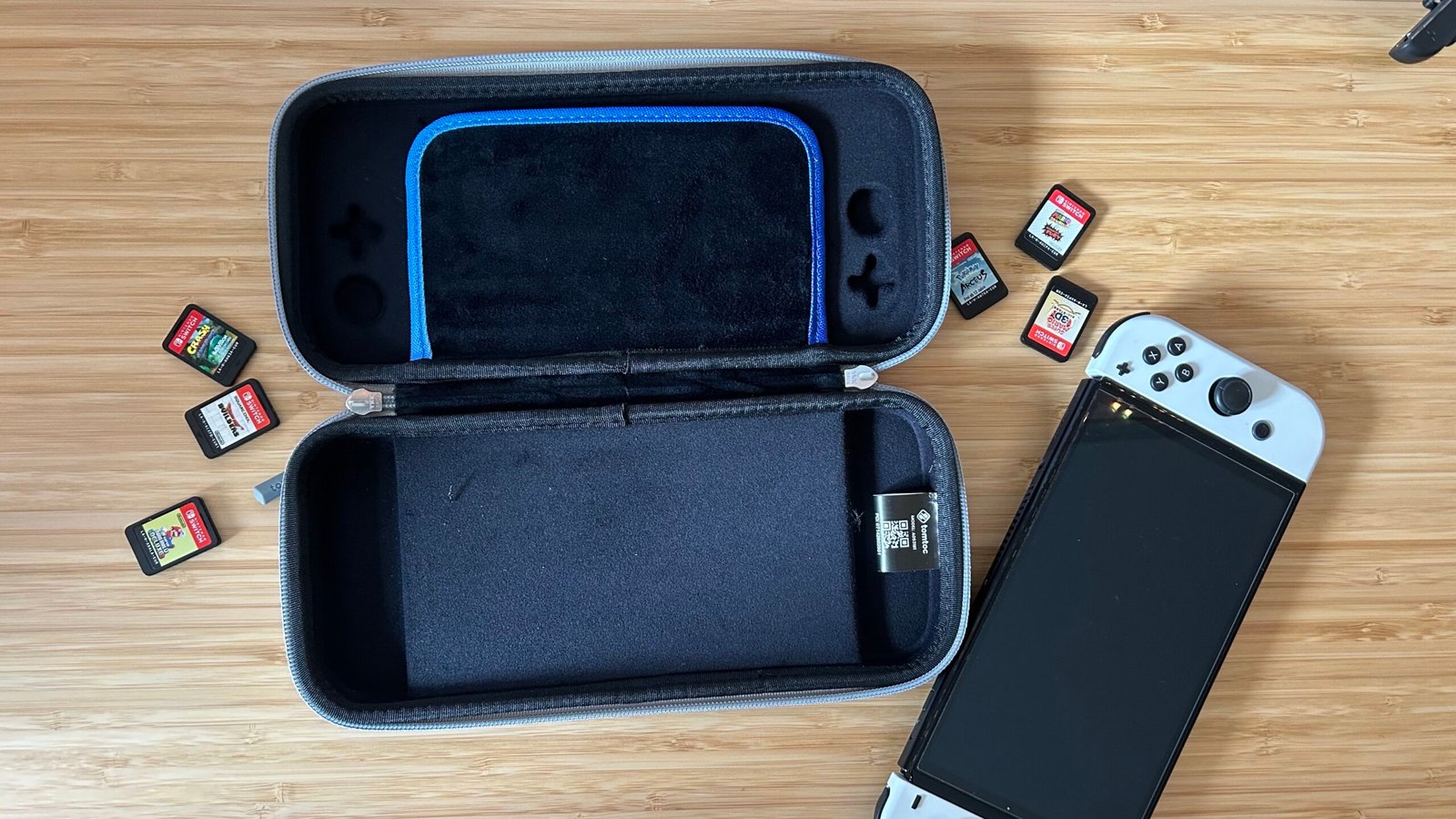 TomToc Nintendo Switch case open on a wooden table with a Nintendo Switch next to it