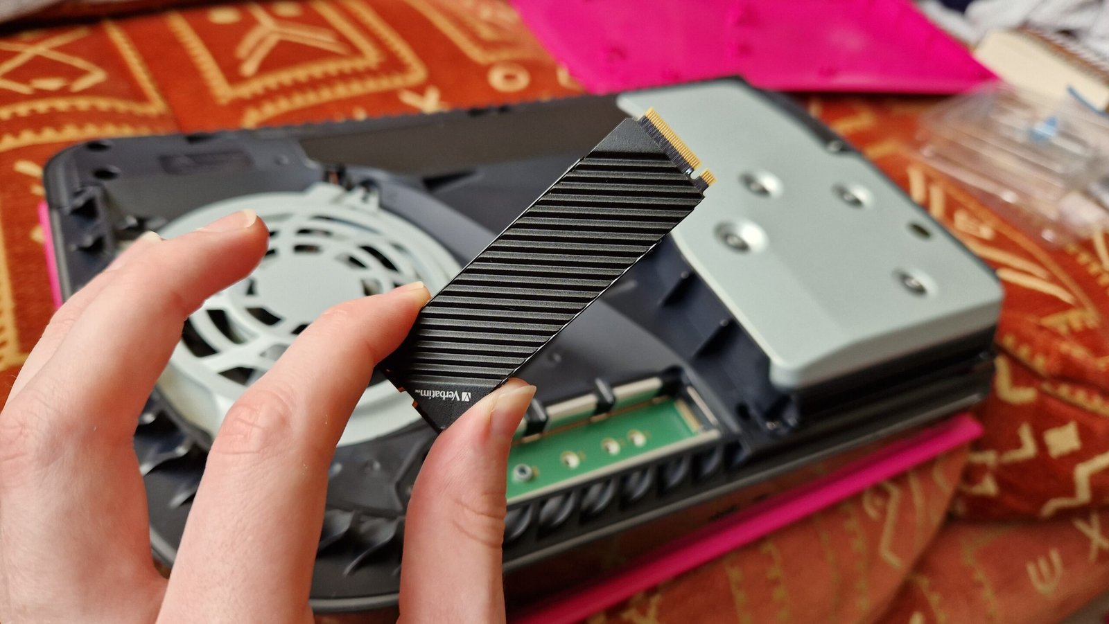 Verbatim Vi7000G in a reviewer's hand above an open PS5 M.2 slot