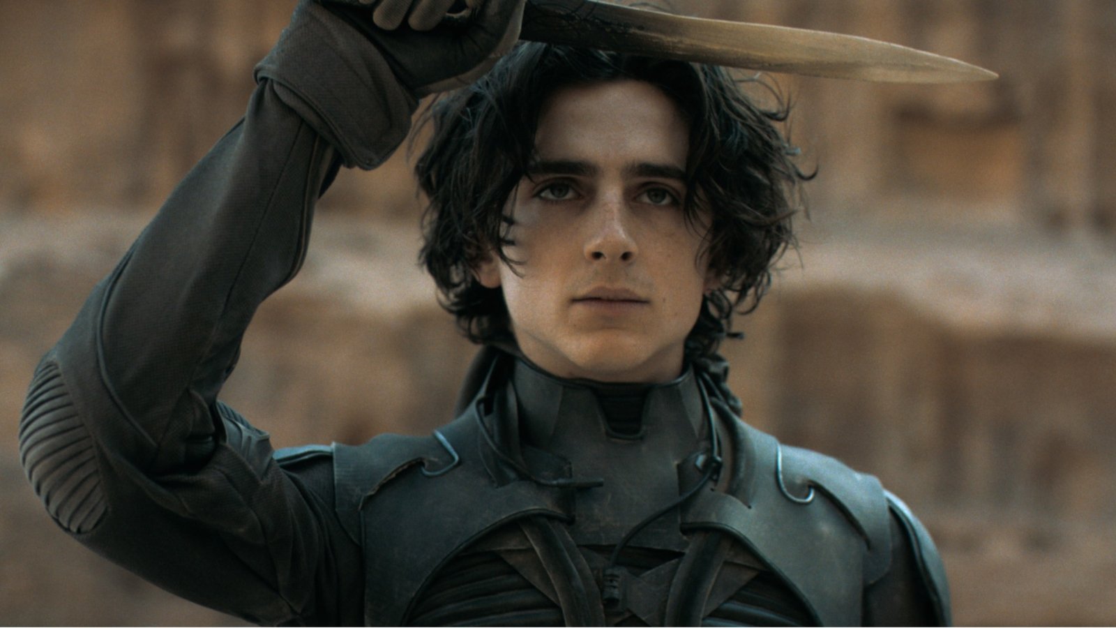 Timothée Chalamet as Paul Atreides holding a knife during the movie Dune. 