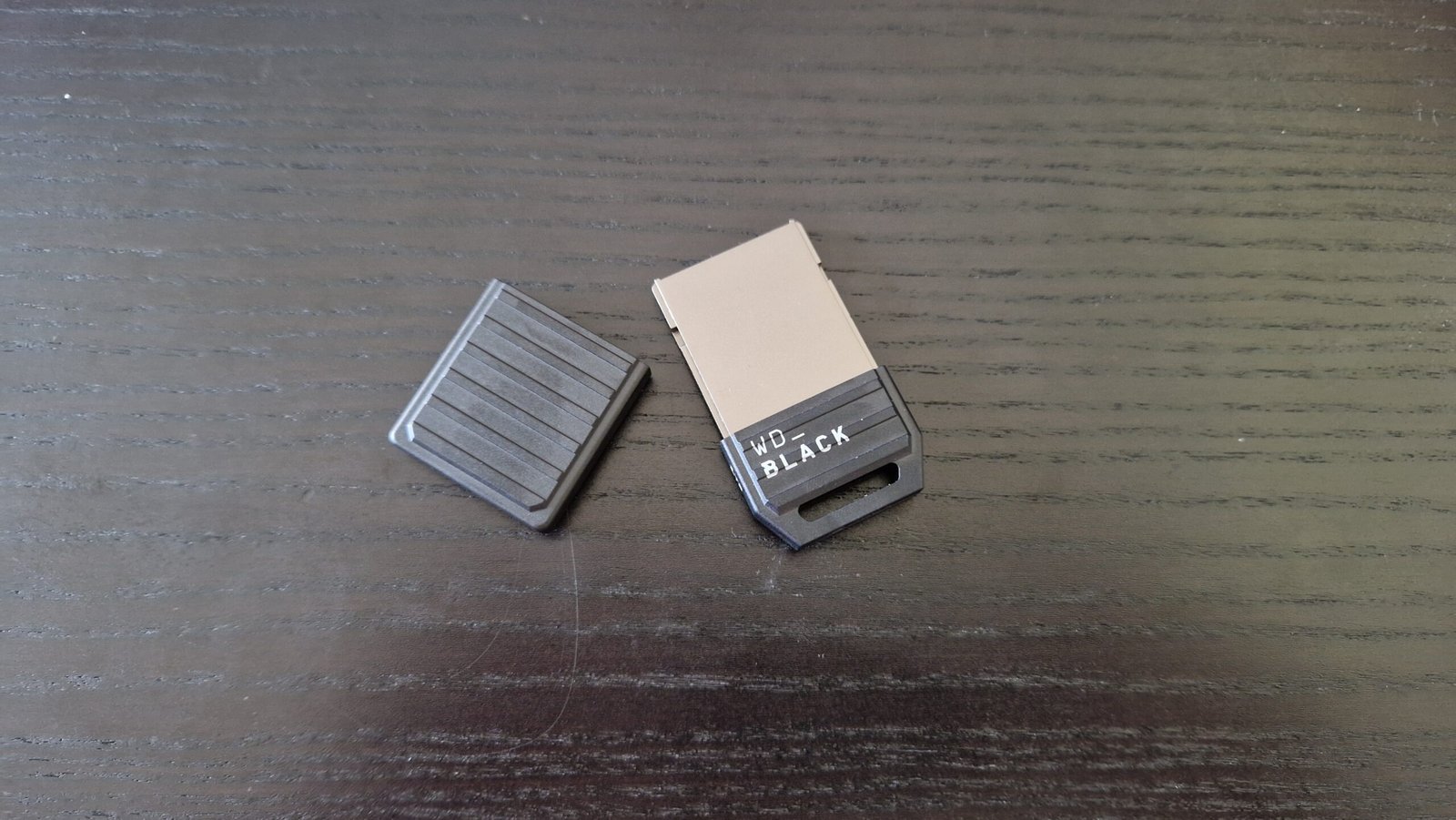 WD Black C50 expansion card for Xbox Series X and S sitting on a black wooden desk with the plastic shield off sitting next to it