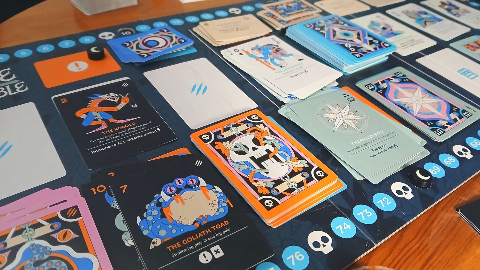 Fame & Fable board with cards across it, laid out on a wooden table