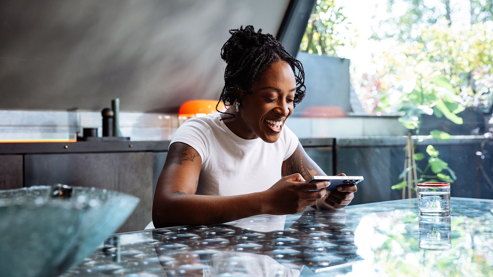 A young black woman playing a mobile game on the Samsung Galaxy S25 in a stylish kitchen