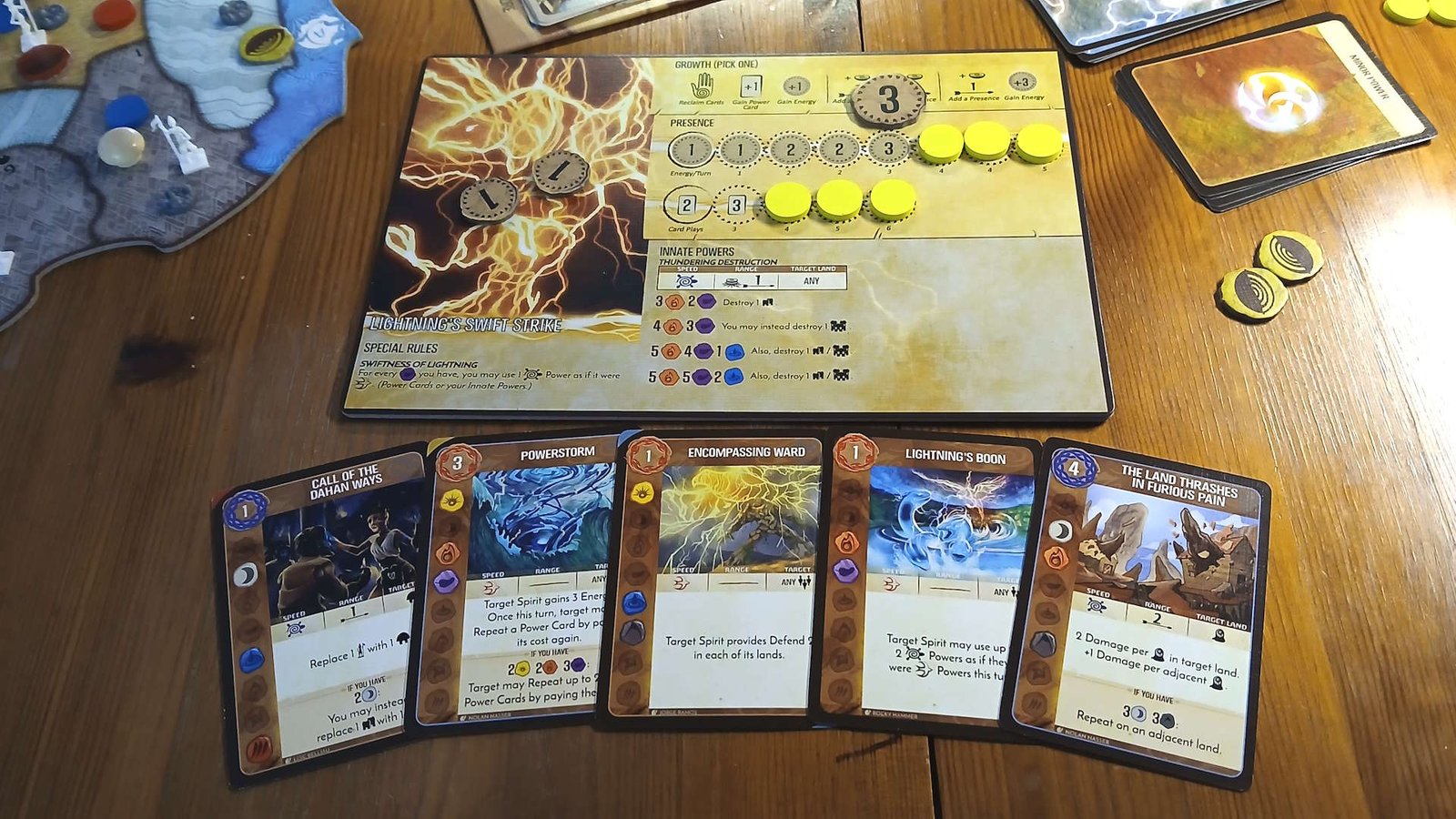 Spirit Island components, cards, and board pieces on a wooden table