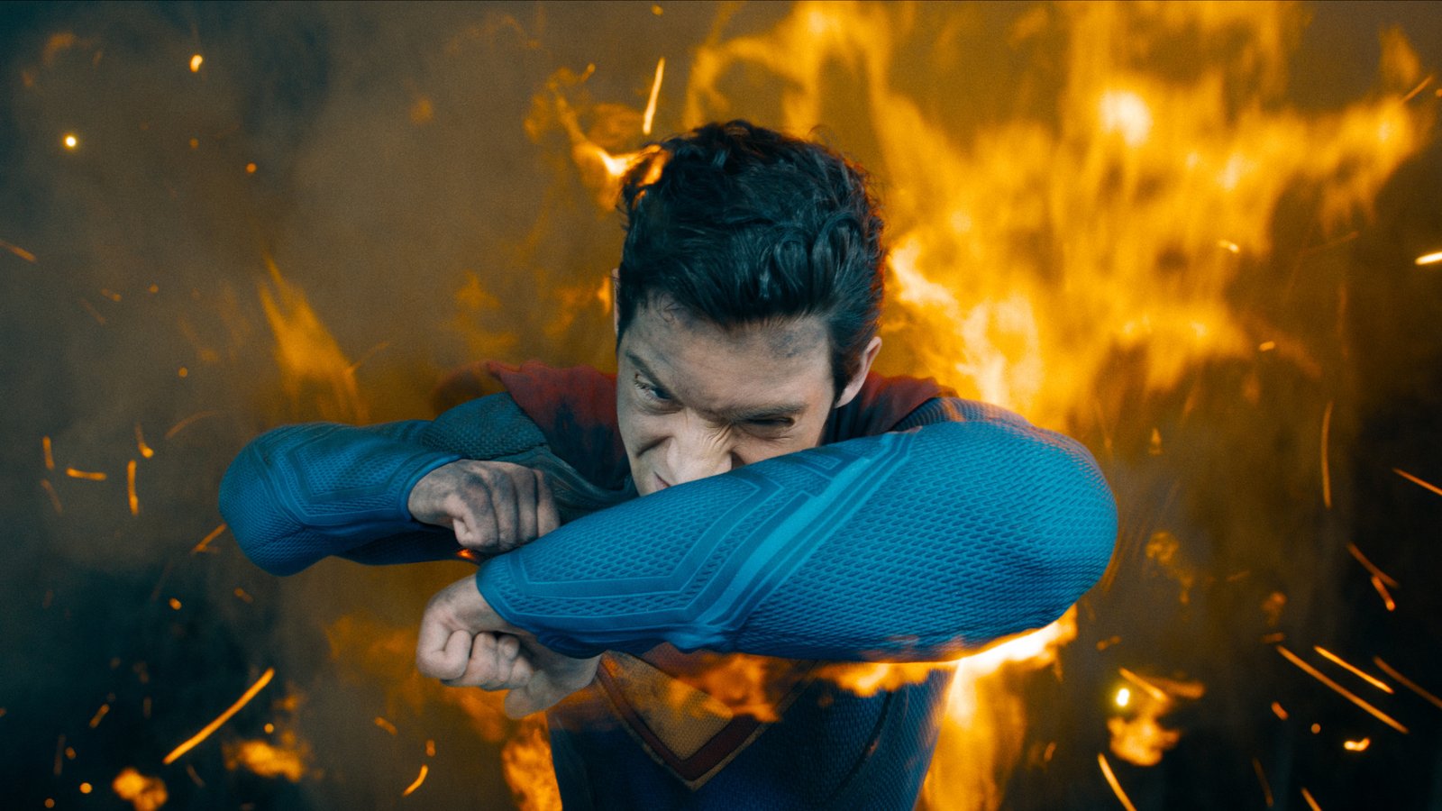David Corenswet as Superman fighting back flames