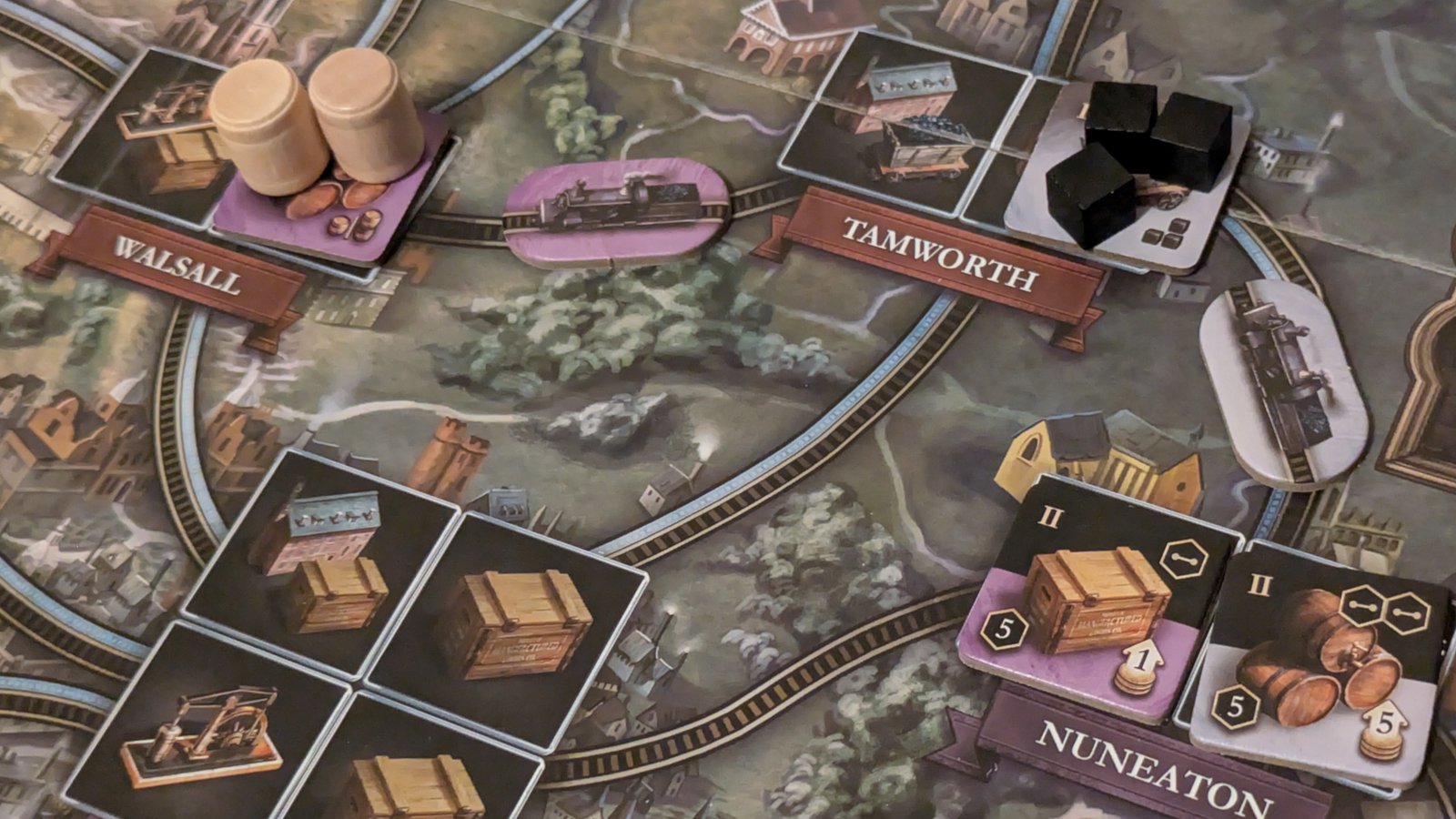 Crate, barrel, and train tokens laid out on the Brass: Birmingham board