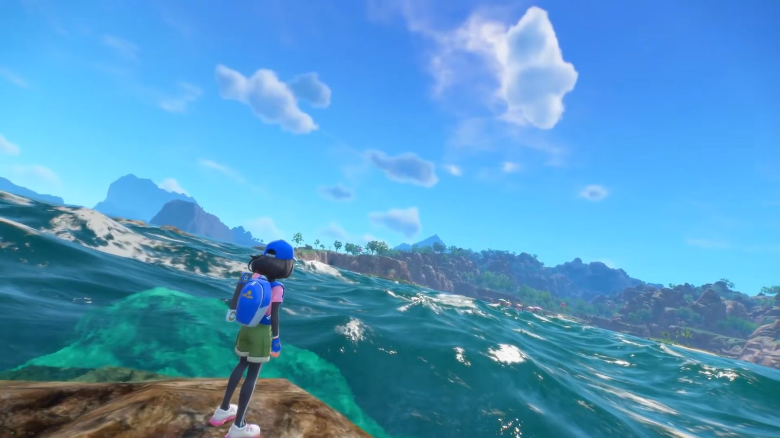 A trainer standing on a rock next to the ocean during Pokemon Winds and Waves