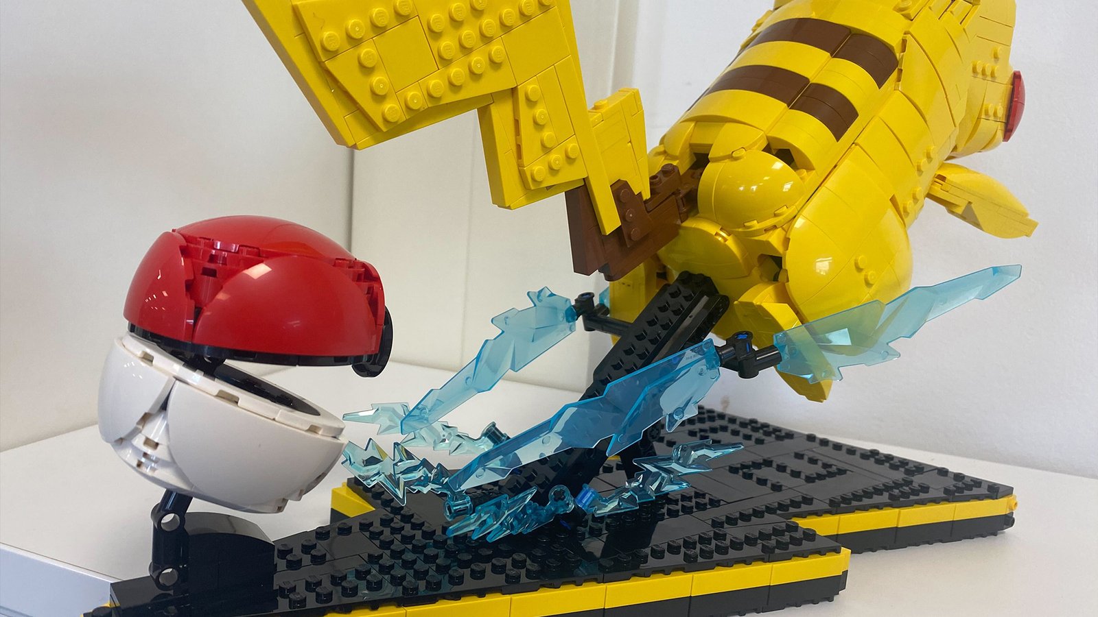 Lego Pikachu and Poke Ball set against a white background, seen from behind to highlight the pole