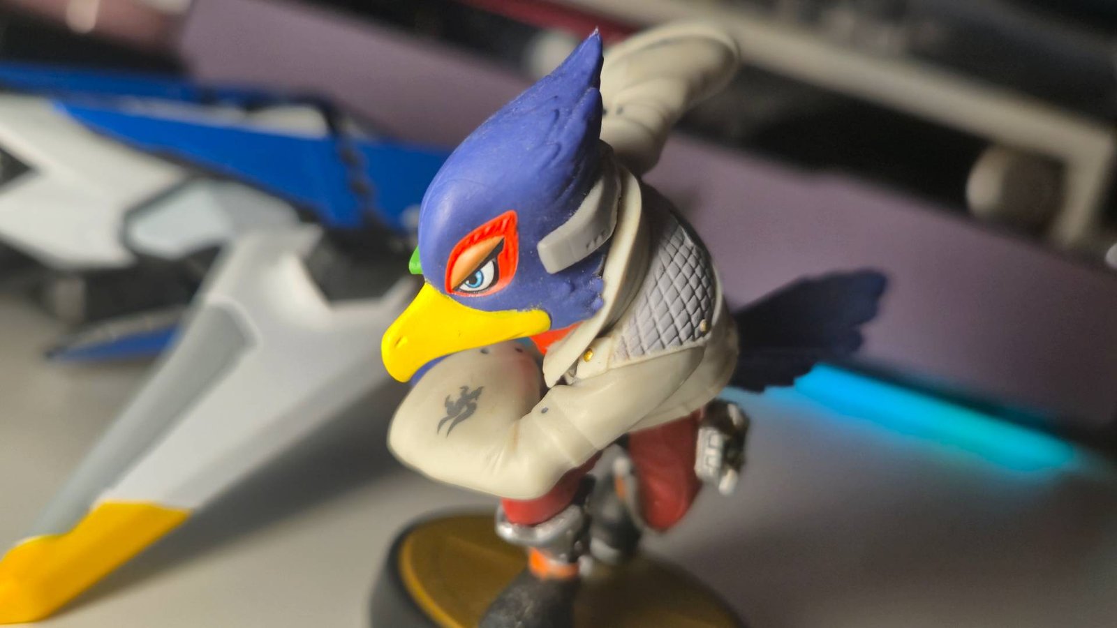 Close up of the Smash Bros Falco amiibo, with a gaming desk behind.