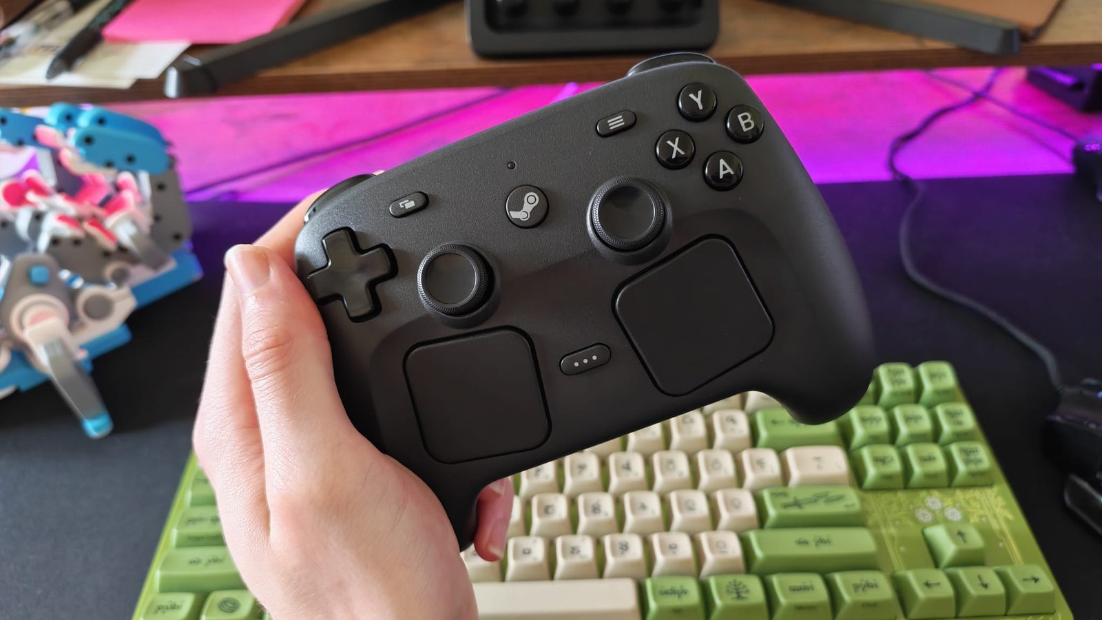 A reviewer holding a Steam Controller over a gaming desk