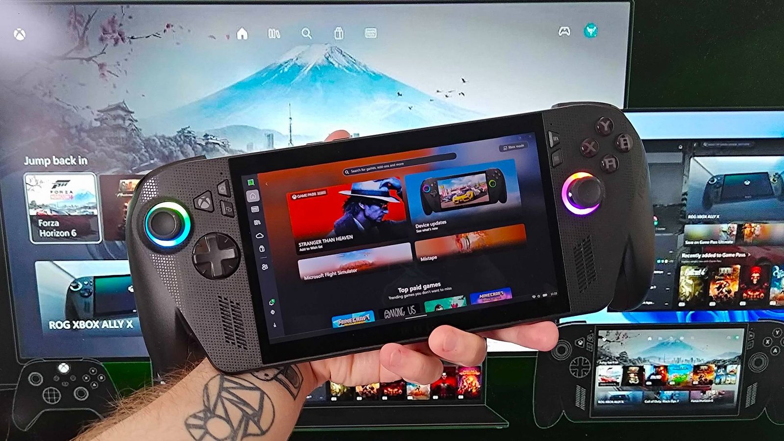 Hand holding ROG Xbox Ally X in front of monitor with Xbox "Consistent Experience" graphic displayed with devices using same UI.