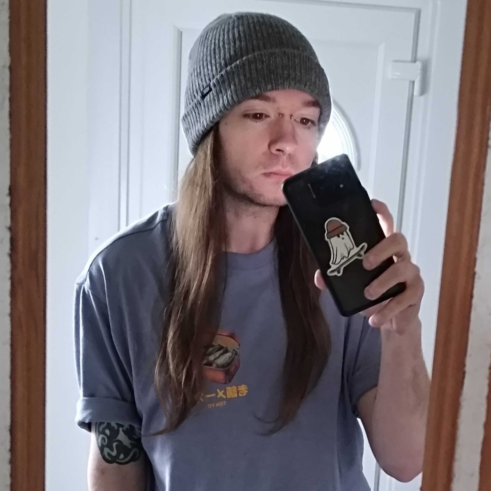 Selfie of Phil Hayton in grey beanie and blue t shirt holding phone.