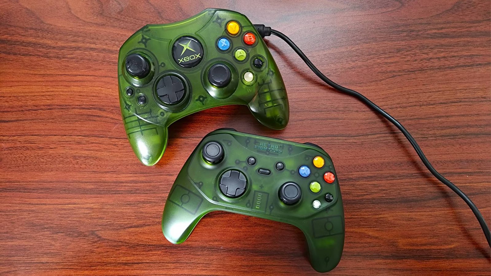 Retro Fighters Hunter sitting under OG Xbox S controller in transparent green sitting on woodgrain desk.